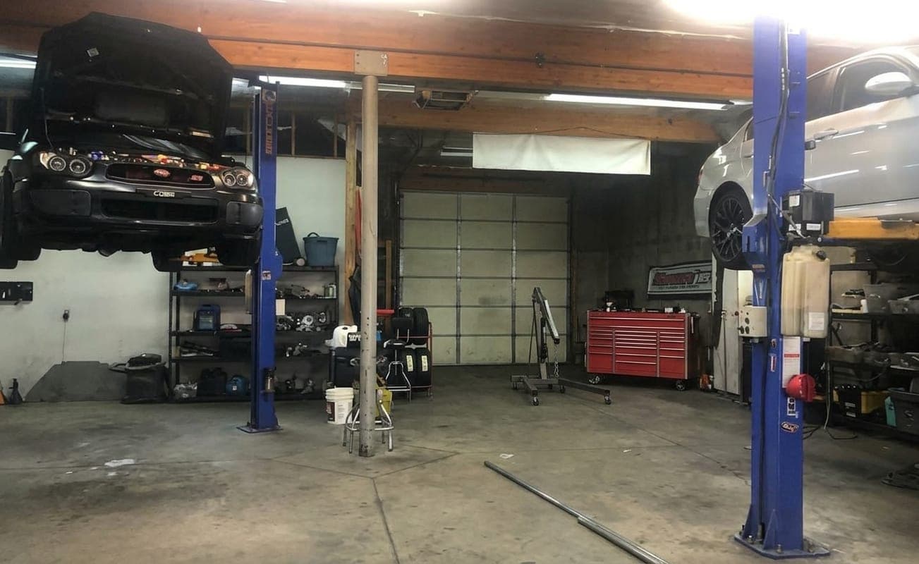 Inside Turbo Lab's shop in Orem: a Subaru STI and a sedan up on two-post lifts
